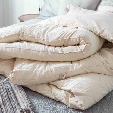 A pile of Sonoma Wool Company blankets made using sustainable wool and 100% cotton fabrics