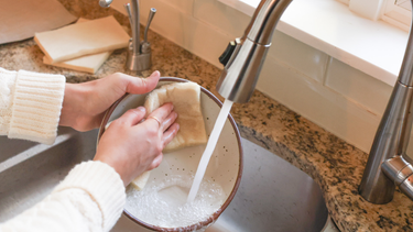 Hands washing dishes with natural wool cleaning products