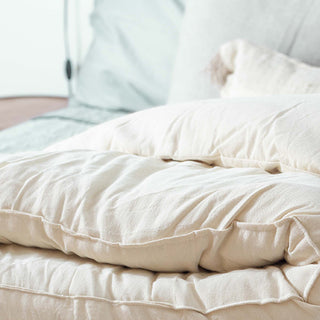 White comforter and pillows, featuring a wool mattress topper for optimal comfort and support.