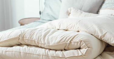 White comforter and pillows, featuring a wool mattress topper for optimal comfort and support.