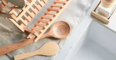 A wooden drying rack and wooden spoons sit on top of a wool drying mat from Sonama Wool Company. 