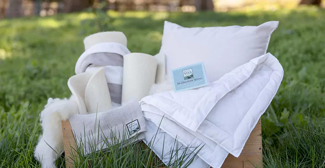 Premium wool bedding collection displayed on green grass showcasing sustainable luxury with crisp white duvet, pillow, and natural wool filling - eco-friendly home essentials for creating the ultimate cozy sanctuary in 2025