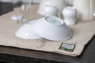 Sustainable wool dish drying mat from Sonoma Wool Company displaying elegant white ceramic bowls, showcasing eco-friendly kitchen solutions and natural absorbency