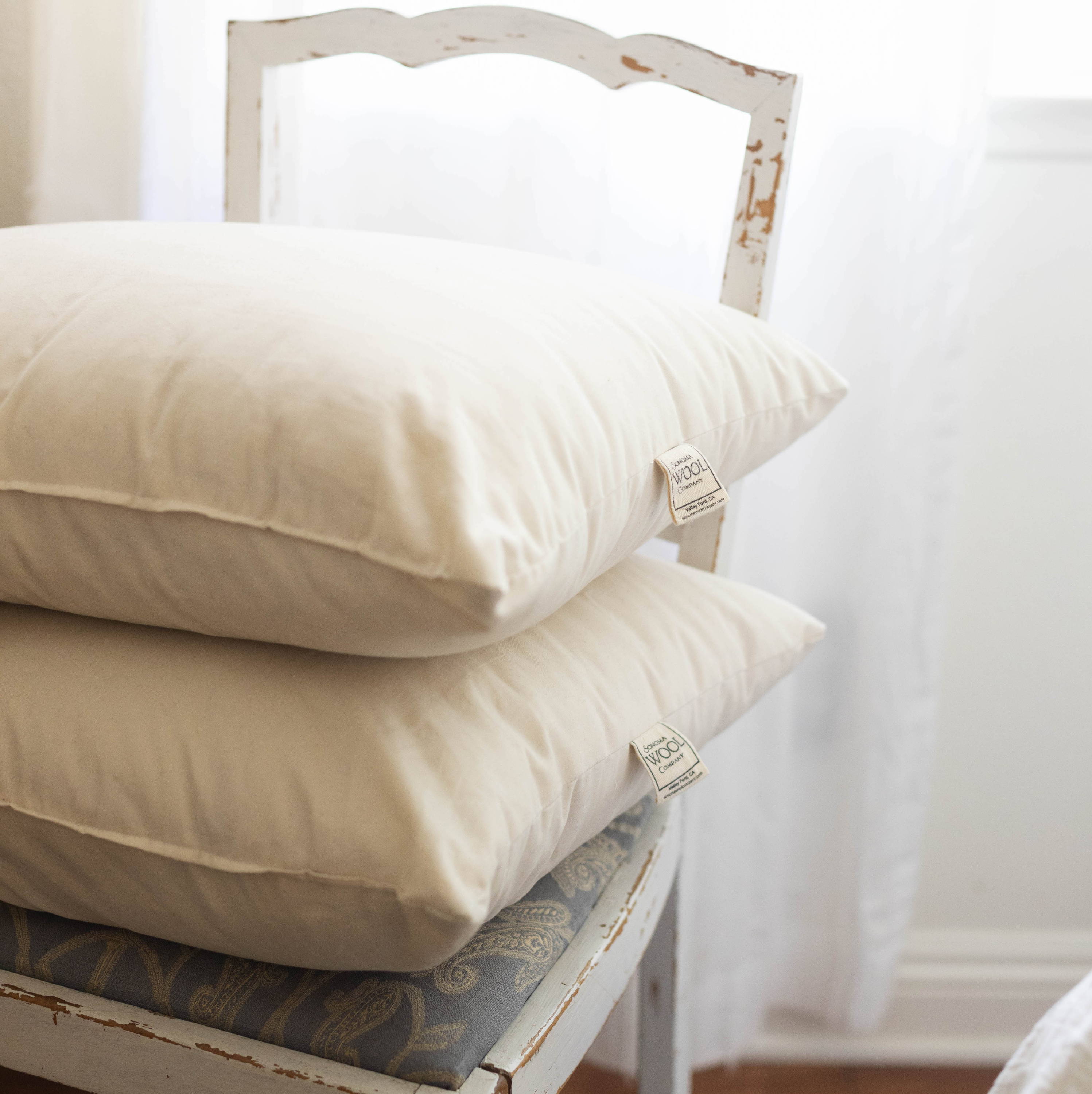 A pile of wool pillows stacked on a wooden chair