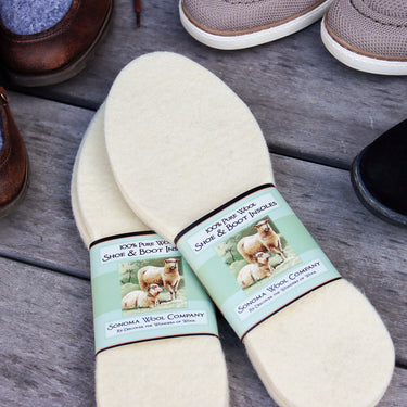 Wool shoe insoles placed beside shoes on wooden floor