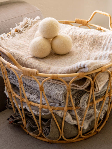 Sonoma Wool Company's Wool Dryer Balls stacked on top of a basket of laundry.