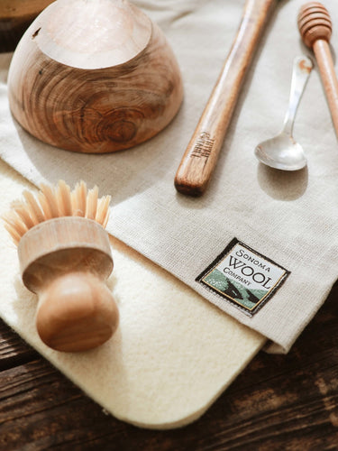 Sonoma Wool Company's Wool Dish Drying Mat with Linen Sleeve on a kitchen counter, with utensils drying on top.