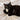 Black cat lounging on wool mat holding a wool cat toy in cozy setting