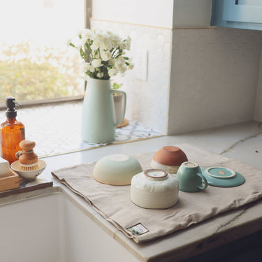 wool dish drying mat with stacked bowls on marble countertop